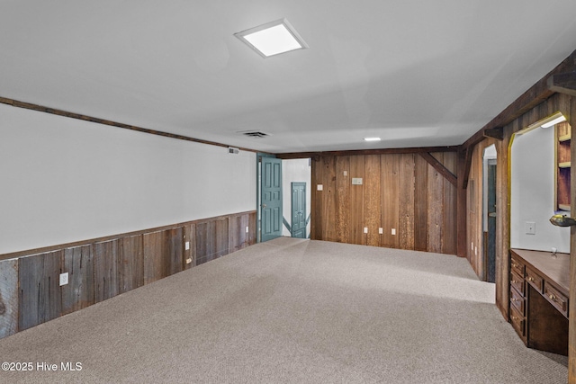 carpeted empty room with visible vents and wood walls