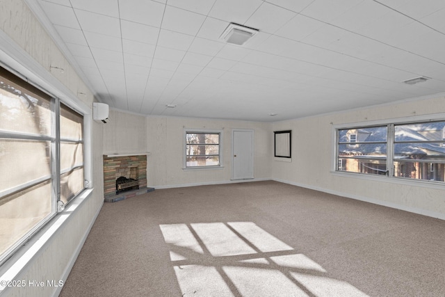 unfurnished living room with visible vents, baseboards, a wall unit AC, carpet, and a fireplace