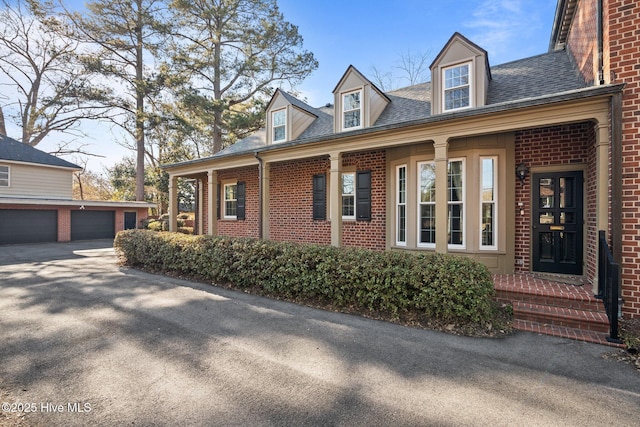 view of property exterior with a garage, an outbuilding, brick siding, and roof with shingles