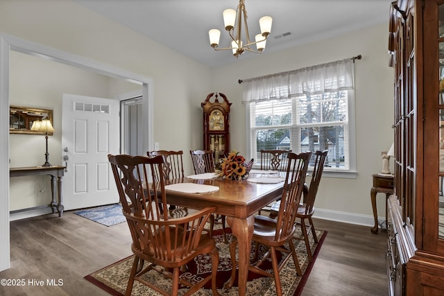 dining area with baseboards, dark wood finished floors, visible vents, and a notable chandelier