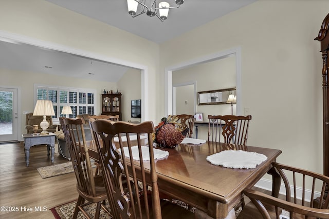 dining space featuring baseboards, a chandelier, and wood finished floors