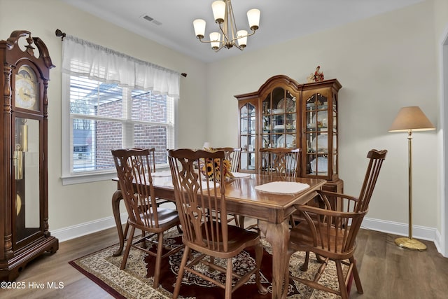 dining area featuring baseboards, visible vents, a notable chandelier, and wood finished floors