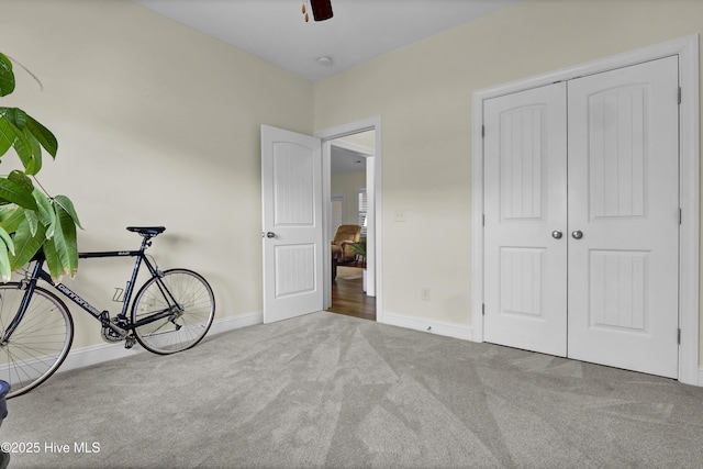 interior space featuring a closet, carpet, a ceiling fan, and baseboards