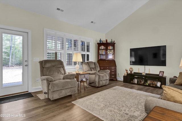 living area featuring vaulted ceiling, wood finished floors, visible vents, and baseboards