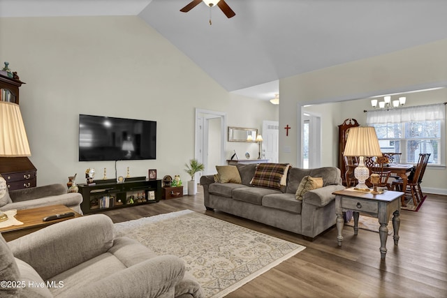 living area with high vaulted ceiling, wood finished floors, and ceiling fan with notable chandelier