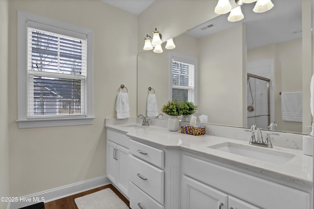 bathroom with visible vents, a sink, a shower stall, and baseboards