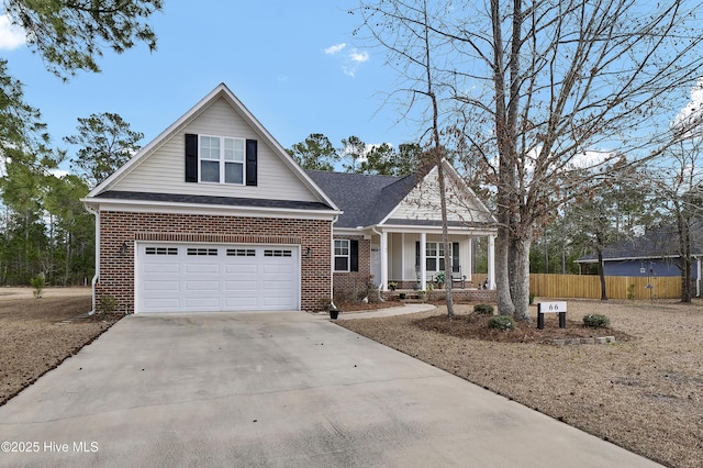 view of front of property with driveway, brick siding, a porch, and fence