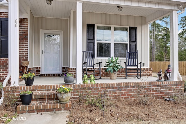 doorway to property featuring covered porch and brick siding