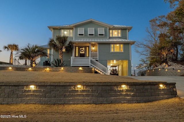 view of front of property featuring a standing seam roof, a fenced front yard, a porch, stairway, and metal roof