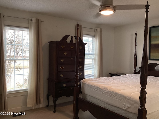 carpeted bedroom with ceiling fan, multiple windows, and a textured ceiling