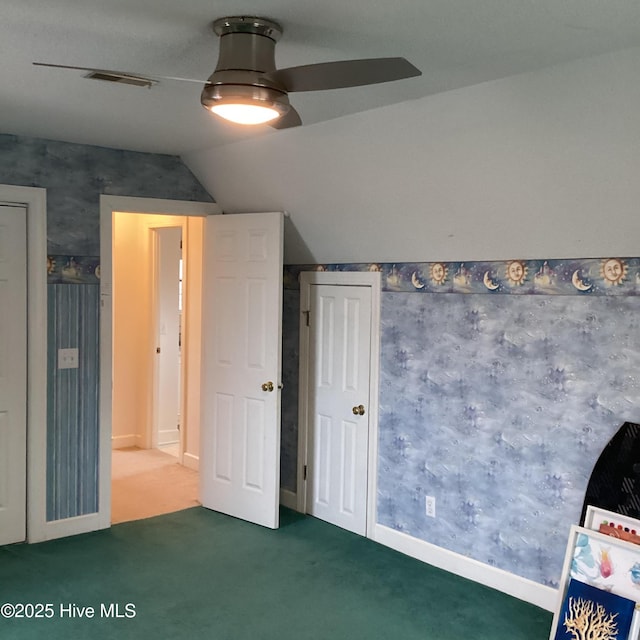 unfurnished bedroom with visible vents, wallpapered walls, ceiling fan, vaulted ceiling, and carpet flooring