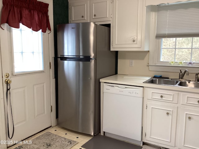 kitchen featuring dishwasher, light countertops, a wealth of natural light, and a sink