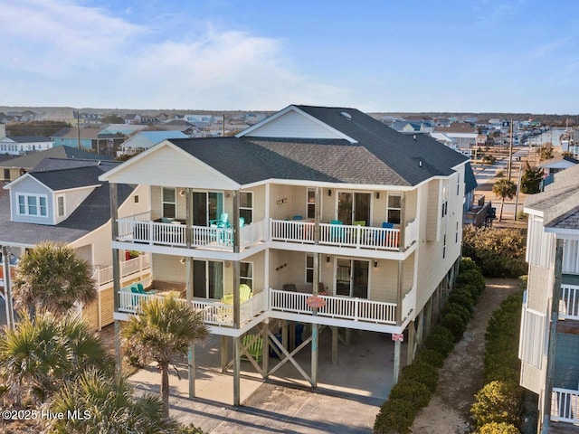 back of property with a balcony, a shingled roof, and a residential view