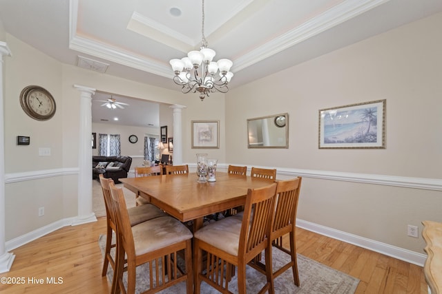 dining room featuring ornamental molding, baseboards, light wood-style floors, decorative columns, and a raised ceiling