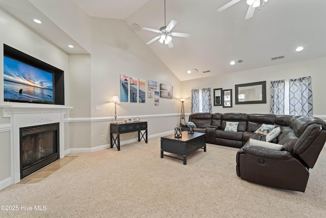 carpeted living room featuring baseboards, visible vents, high vaulted ceiling, a fireplace with flush hearth, and ceiling fan