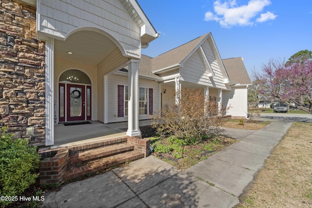 property entrance with stone siding and a shingled roof