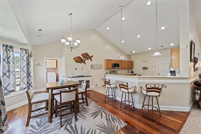 dining room with washer / clothes dryer, wood finished floors, baseboards, and high vaulted ceiling