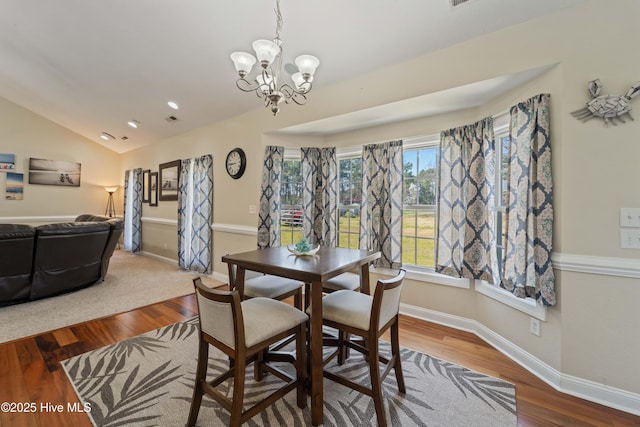 dining space featuring an inviting chandelier, vaulted ceiling, wood finished floors, and baseboards