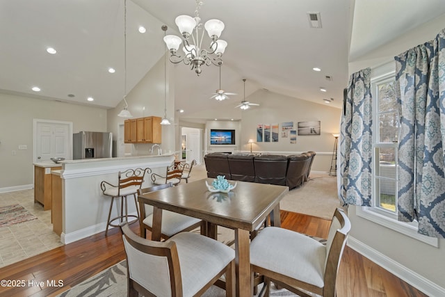 dining room with light wood finished floors, visible vents, baseboards, and vaulted ceiling