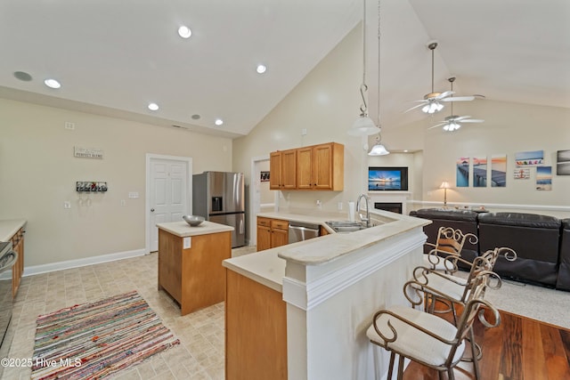 kitchen with a center island, a kitchen breakfast bar, appliances with stainless steel finishes, a peninsula, and a sink