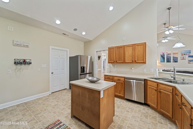 kitchen with a sink, stainless steel appliances, a kitchen island, and light countertops