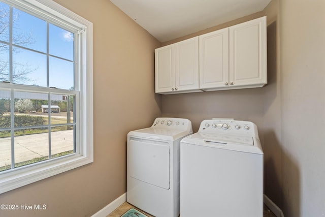 clothes washing area with washer and dryer, cabinet space, and baseboards