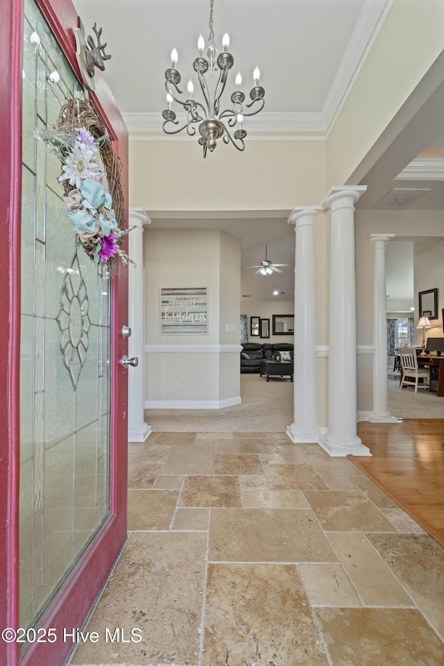 entryway featuring ornamental molding, a ceiling fan, stone tile flooring, decorative columns, and baseboards