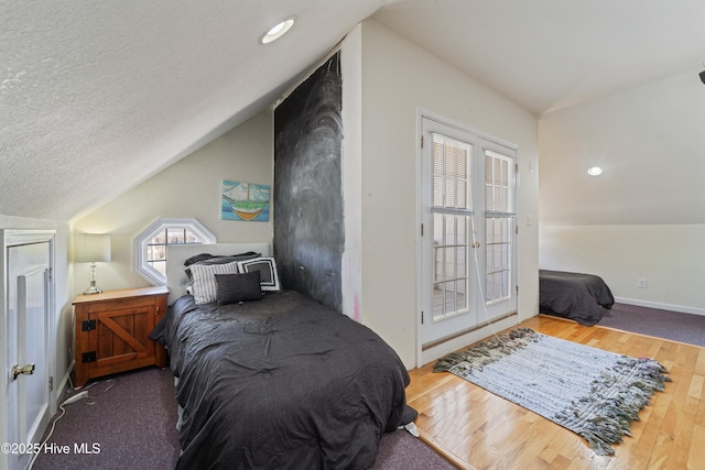 bedroom featuring wood finished floors, recessed lighting, vaulted ceiling, french doors, and a textured ceiling