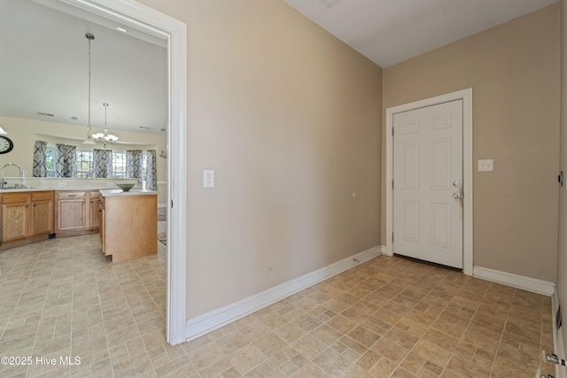 interior space featuring baseboards, a chandelier, and a sink