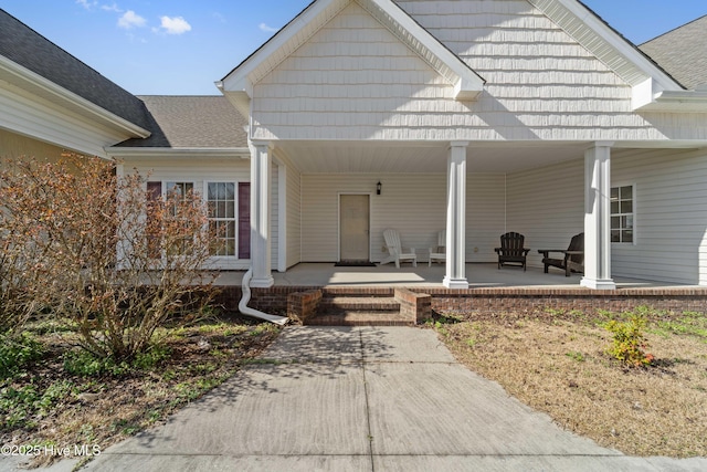 property entrance featuring covered porch and roof with shingles