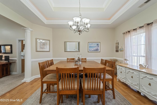 dining area featuring a raised ceiling, decorative columns, visible vents, and light wood finished floors