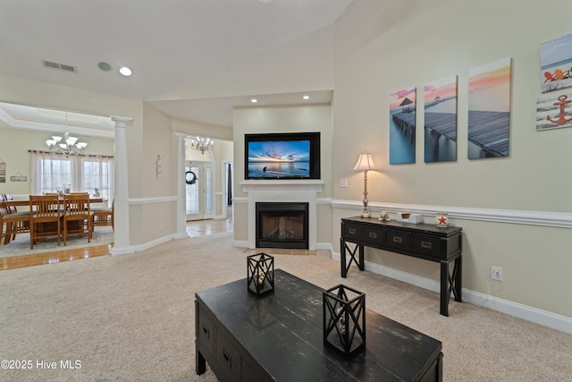 carpeted living room with visible vents, a notable chandelier, a glass covered fireplace, recessed lighting, and baseboards