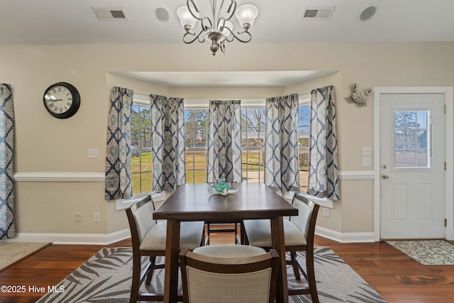 dining space featuring visible vents, an inviting chandelier, and wood finished floors