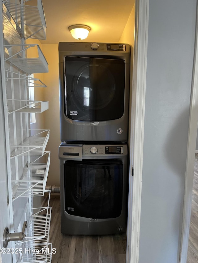 washroom featuring wood finished floors, laundry area, and stacked washer / dryer