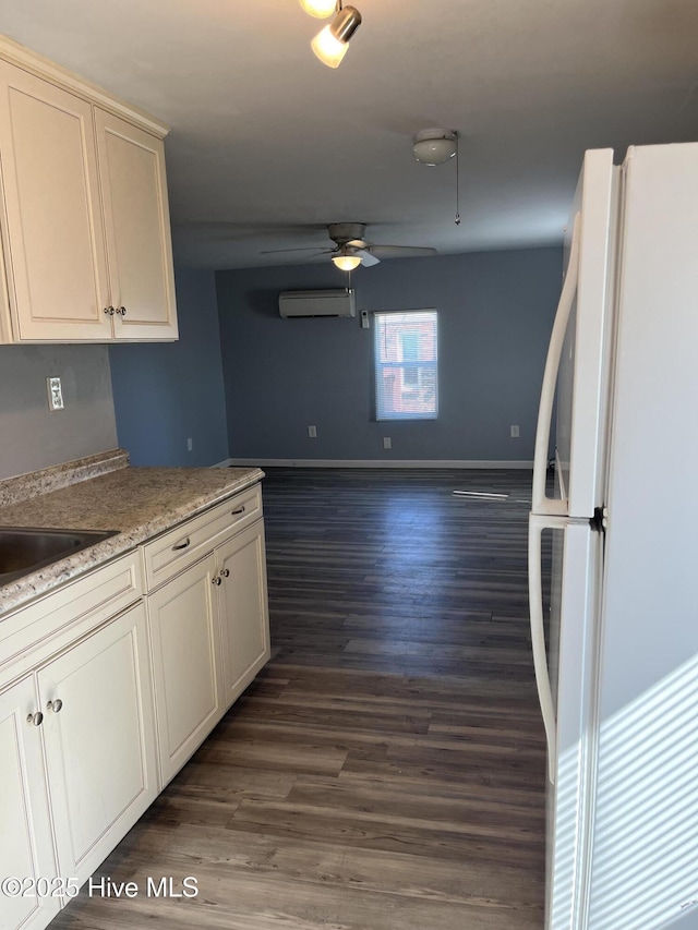 kitchen featuring a wall mounted air conditioner, dark wood-type flooring, freestanding refrigerator, baseboards, and ceiling fan