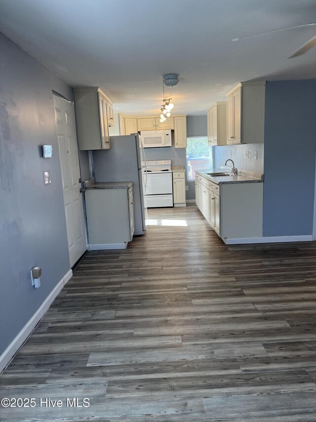 kitchen with white appliances, dark wood-type flooring, baseboards, and a sink