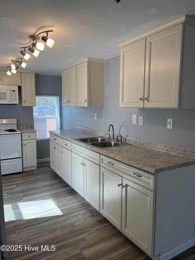 kitchen featuring white appliances, wood finished floors, and a sink
