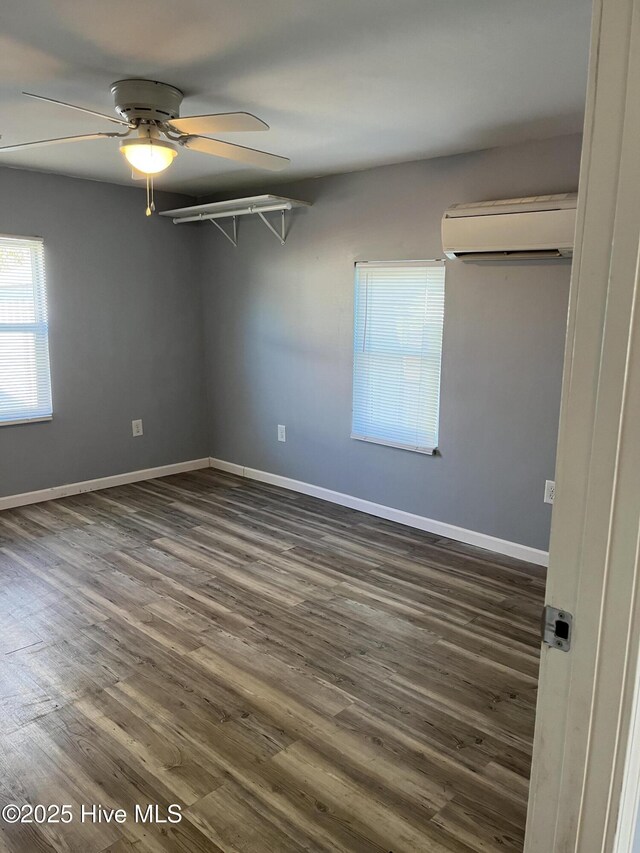 unfurnished room featuring baseboards, a wall mounted AC, ceiling fan, and dark wood-style flooring