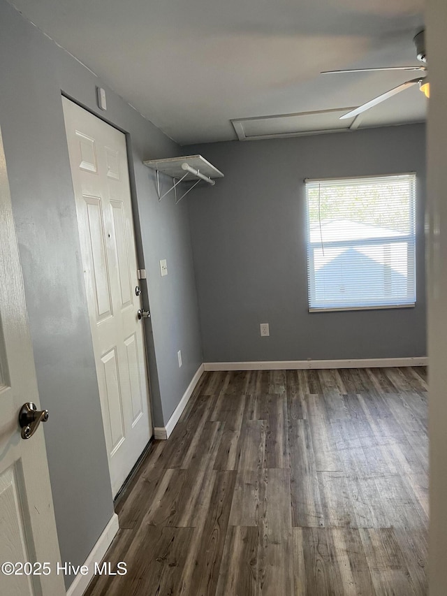 interior space featuring baseboards, attic access, ceiling fan, and dark wood-style flooring
