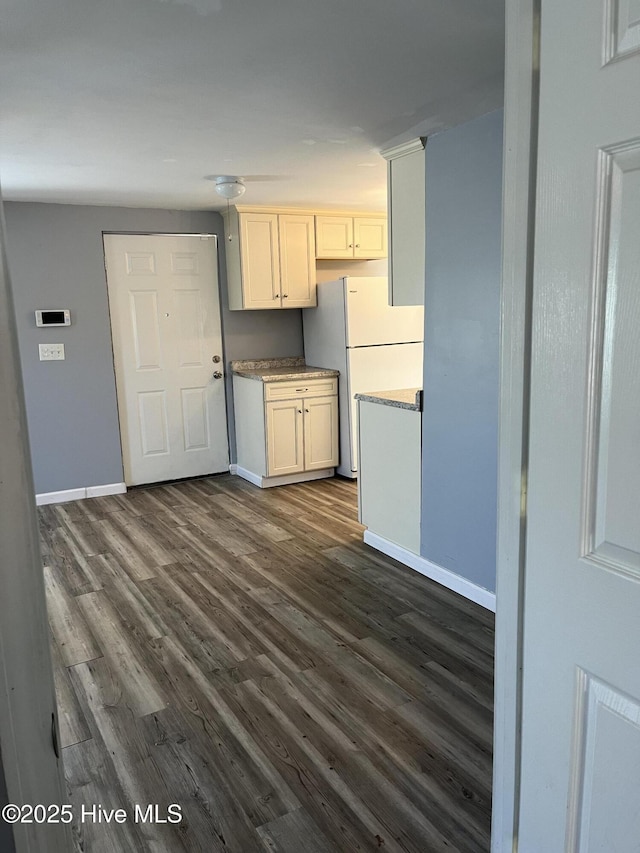kitchen with baseboards, dark wood-style floors, light countertops, and freestanding refrigerator