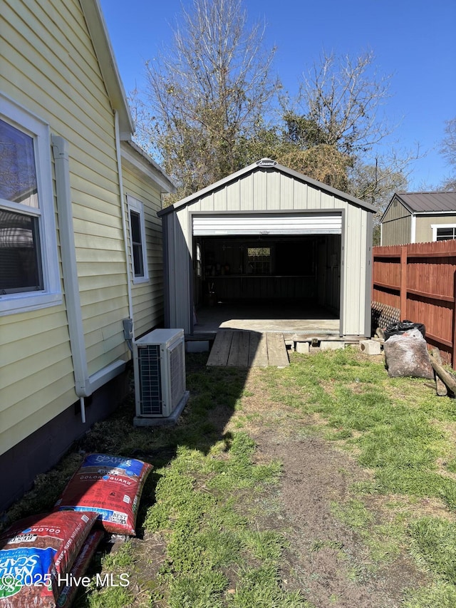 detached garage with a storage shed, cooling unit, and fence