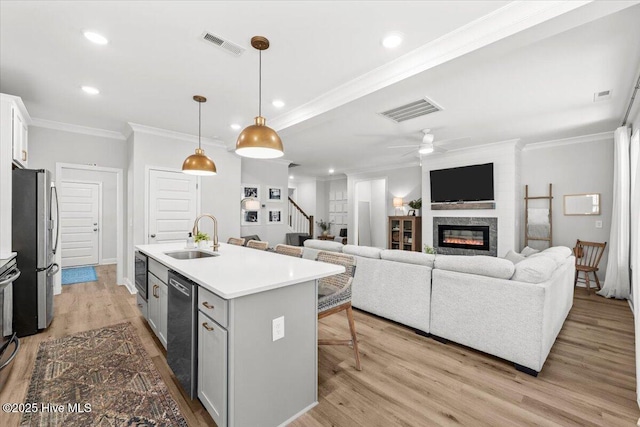 kitchen featuring visible vents, appliances with stainless steel finishes, a sink, and a glass covered fireplace