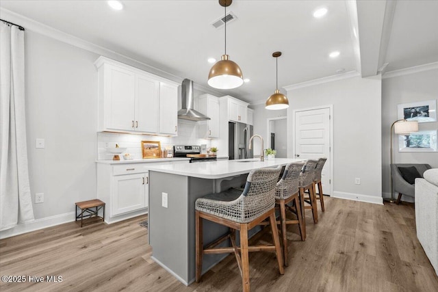 kitchen featuring visible vents, wall chimney exhaust hood, ornamental molding, stainless steel appliances, and backsplash