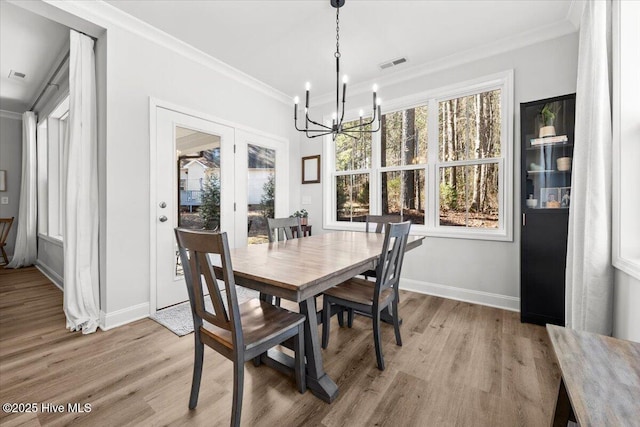 dining space with visible vents, crown molding, light wood-style flooring, and baseboards