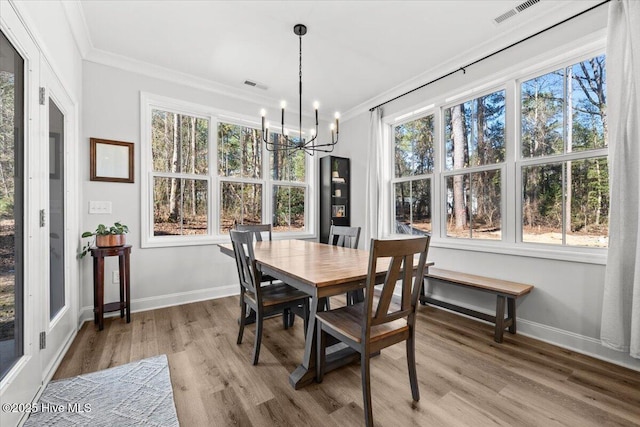 dining room featuring light wood-style floors, baseboards, visible vents, and ornamental molding