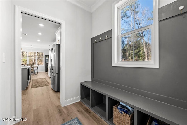 mudroom with an inviting chandelier, light wood-style flooring, ornamental molding, and baseboards