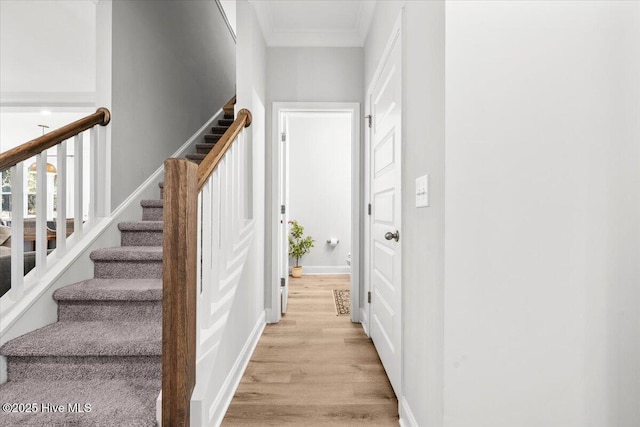 interior space featuring ornamental molding, light wood-type flooring, baseboards, and stairs