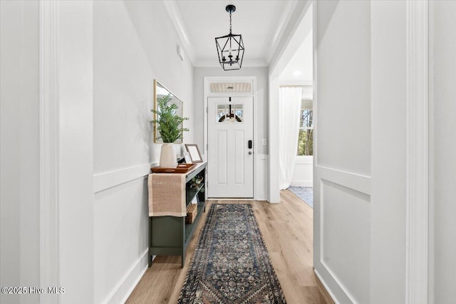 foyer with ornamental molding and light wood-style floors