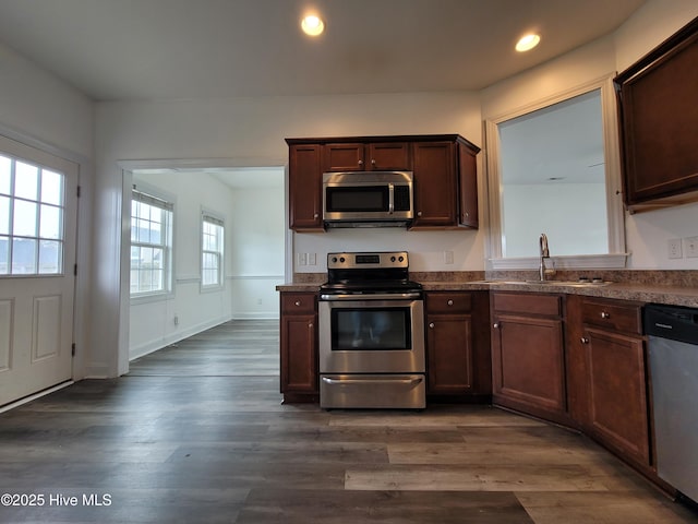 kitchen with dark wood-type flooring, dark countertops, and appliances with stainless steel finishes