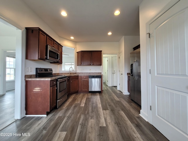 kitchen with baseboards, recessed lighting, a sink, dark wood-type flooring, and appliances with stainless steel finishes